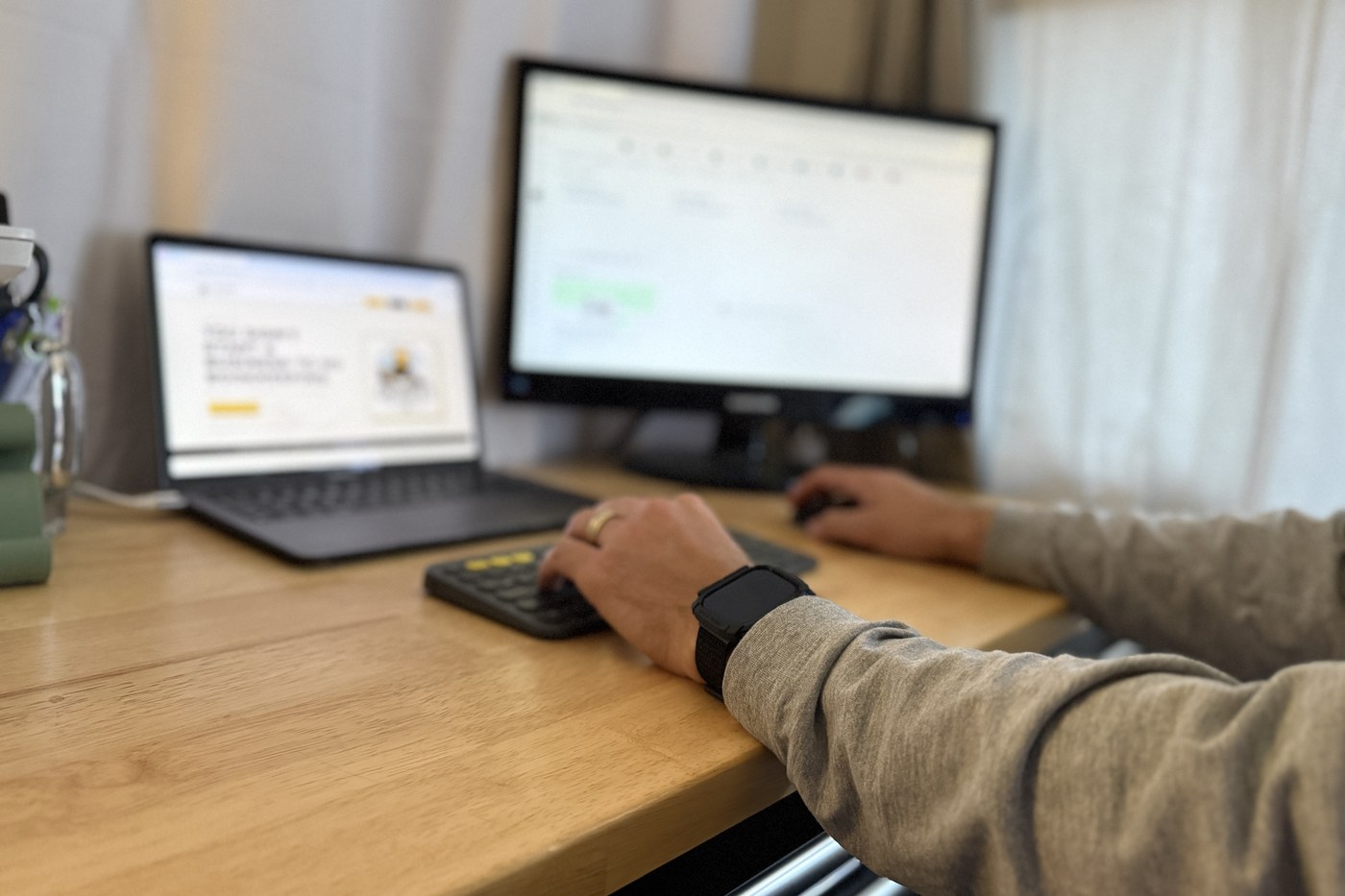 A desk with two screens, one showing the Grumbee's Bookkeeping website and the other a QuickBooks Online dashboard